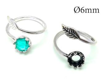 May include: Two silver-toned open rings featuring a leaf design on one end and a crown-style setting on the other. One ring holds a round, bright green gemstone, while the other setting is empty. The text Ø6mm is visible in the upper right corner.