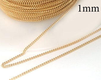 May include: A spool of gold-colored chain, with a 1mm thickness, is displayed against a white background. The chain is tightly coiled, with a portion unraveled to show its texture and detail. The chain is likely used for jewelry making or crafting.
