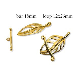 Puede incluir: Cierres de joyería dorados en forma de hoja. La imagen muestra un cierre de barra de 18 mm de largo y un cierre de bucle en forma de hoja de 12x26 mm. Los cierres están diseñados con intrincados detalles de venas de hojas.