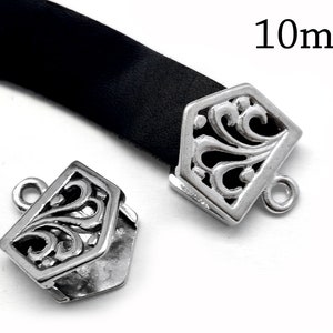 Puede incluir: Dos cierres de metal plateado con un diseño floral decorativo. Cada cierre tiene un bucle en un lado y un agujero en el otro. Los cierres miden 10 mm.