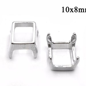 Könnte beinhalten: Zwei silberfarbene Metallfassungen für einen rechteckigen Stein von 10x8mm. Die Fassungen haben vier Krallen, um den Stein zu halten.