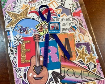 May include: A set of colorful stickers featuring a guitar, stars, a rainbow pennant with the word "TOUR" on it, and other designs. The stickers are on a pink background with a blue ribbon.