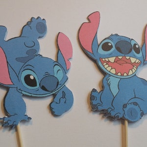 Puede incluir: Dos personajes de dibujos animados Stitch azules y rosas de la pel&iacute;cula de Disney Lilo & Stitch. Los personajes est&aacute;n en palos de madera, perfectos para decorar tartas o fiestas.