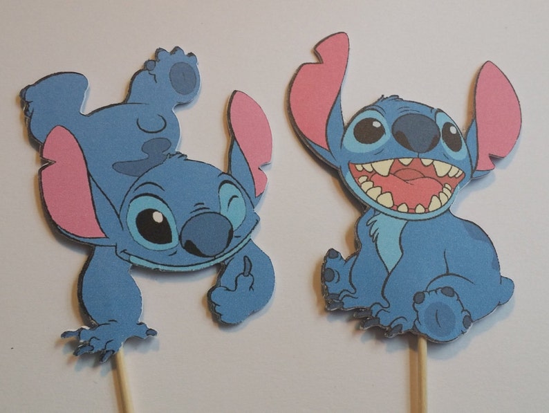 Puede incluir: Dos personajes de dibujos animados Stitch azules y rosas de la pel&iacute;cula de Disney Lilo & Stitch. Los personajes est&aacute;n en palos de madera, perfectos para decorar tartas o fiestas.