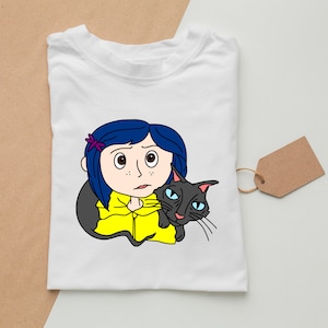 May include: A white t-shirt with a cartoon illustration of a girl with blue hair and a black cat. The girl is wearing a yellow raincoat and has a purple flower in her hair. The cat is looking at the viewer.