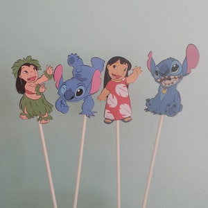 May include: Four character cutouts from the animated film Lilo & Stitch, each attached to a white stick. The characters include Lilo in a red dress, Stitch in blue, and two other characters in green and blue outfits.