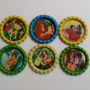 May include: Six colorful, round bottle caps featuring images of characters from the animated movie Tarzan. The caps have scalloped edges in yellow, blue, and green. The images depict scenes with Tarzan, Jane, and other characters.