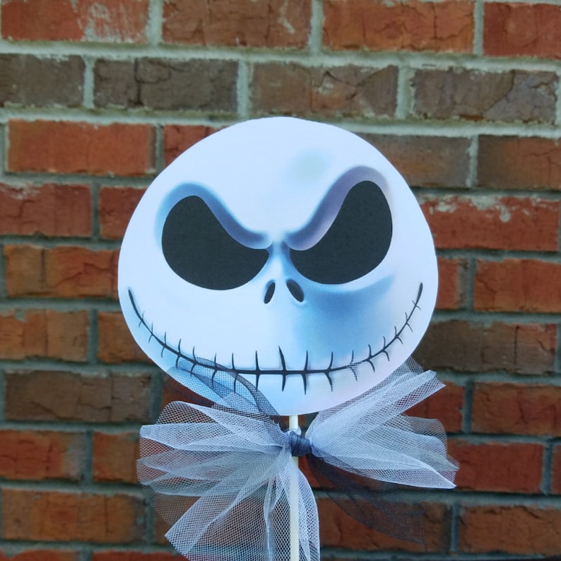 Pu&ograve; includere: Un ritaglio di viso bianco di Jack Skellington con un fiocco di tulle bianco e nero attaccato a un bastone di legno. Il ritaglio &egrave; un personaggio popolare del film "Nightmare Before Christmas".