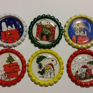 May include: Six round Christmas-themed coasters featuring Snoopy and Woodstock. Each coaster has a different design, including Snoopy by a fireplace, Snoopy with a Christmas tree, and Snoopy in the snow. The coasters have colorful rims.