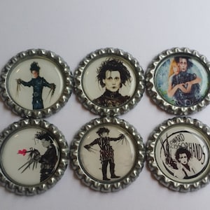 May include: Six silver bottle caps with images of Edward Scissorhands from the movie Edward Scissorhands. The images include Edward with his scissors, Edward with a heart, and Edward with a woman.