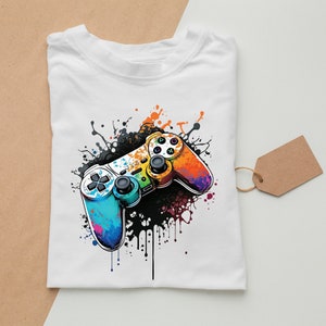 May include: A white t-shirt with a colorful video game controller graphic. The controller is surrounded by colorful paint splatters.