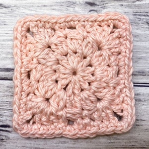 May include: A pink crocheted square with a textured pattern. The square is made with a single crochet stitch and has a border of double crochet stitches.