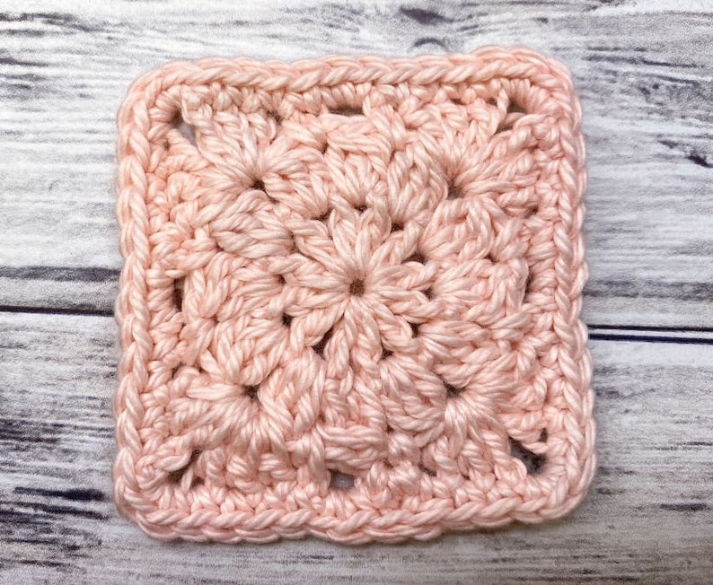 May include: A pink crocheted square with a textured pattern. The square is made with a single crochet stitch and has a border of double crochet stitches.