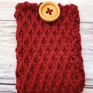 May include: A red knitted phone case with a wooden button.