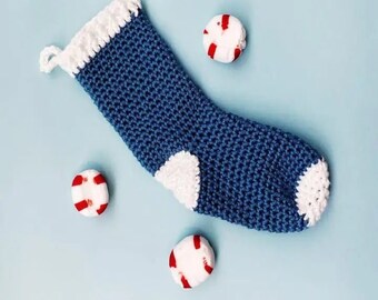 May include: A blue crocheted stocking with white trim and a white patch on the heel. Three red and white candy canes are scattered around the stocking.