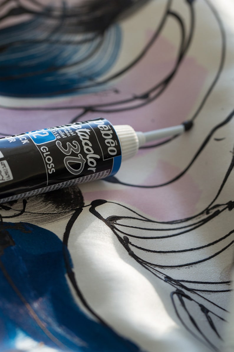 May include: A black and blue bottle of Pebeo Tacolor 3D gloss paint with a white cap and a silver applicator tip. The bottle is lying on a white fabric with black and blue abstract designs.
