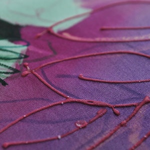 May include: Close-up of a purple fabric with a design of red lines and swirls. The fabric has a textured surface.