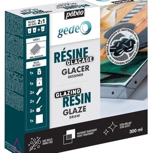 May include: A box of Pebeo Gedeo Glazing Resin, a clear, highly transparent resin for glazing and drawing. The box includes two bottles of resin, a pair of gloves, a mixing stick, a measuring cup, and a small square container. The box is labeled with the product name, brand, and instructions for use. The resin is 300 ml and is ultra-glossy.
