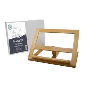 May include: A Studio 22 Hamsterley Bamboo Table Easel is made of natural bamboo and features a foldable design. The easel is shown in a folded position with its box in the background. The box has the Studio 22 logo and the product name.
