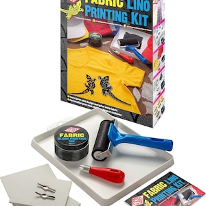 Op de afbeelding: Een Fabric Lino Printing Kit met een doos met een geel T-shirt met hagedisontwerpen. De kit bevat zwarte inkt, een roller, snijgereedschap en drukblokken. Op de doos staat "Fabric Lino Printing Kit".