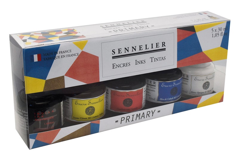 May include: A boxed set of Sennelier primary inks, made in France. The set includes five small glass jars of ink in various colors, including yellow, red, blue, black, and white. The packaging features the brand name and the text "PRIMARY".