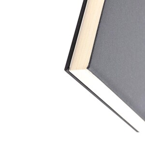 May include: Close-up of the top edge of a black hardcover book with a white spine.