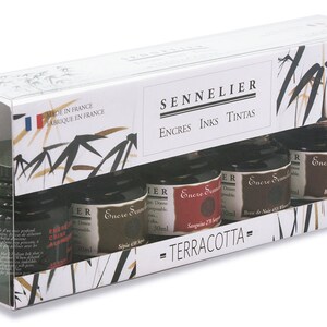 May include: A set of five Sennelier Terracotta ink bottles, each containing 30 ml. The bottles are displayed in a clear plastic box with the brand name and "Made in France" printed on the packaging. The inks are various shades of brown and red.
