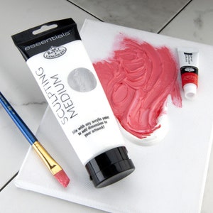 May include: A white tube of Royal Langnickel essentials sculpting medium with the text "Mix with any acrylic paint to add dimension to your artwork!"  A small tube of acrylic paint is also visible in the image.