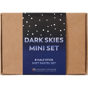 May include: A brown cardboard box with a dark blue and black label. The label says "DARK SKIES MINI SET" and "8 HALF STICK SOFT PASTEL SET". The brand name "UNISON COLOUR" is also visible.