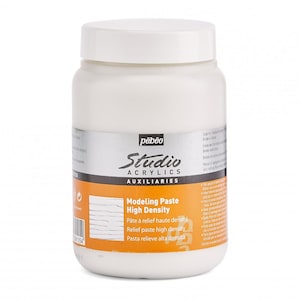 Op de afbeelding: Witte plastic pot met Pebeo Studio Acrylics Modelleerpasta Hoge Dichtheid. De pot heeft een zwart en zilver etiket met de tekst "Modeling Paste High Density" en de woorden "Pâte à relief haute densité", "Relief paste high density", en "Pasta relieve alta densità".