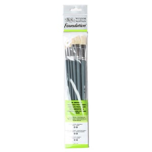 Op de afbeelding: Een set van zes Winsor & Newton Foundation olieverfpenselen met natuurlijke borstels en grijze kunststof handvatten. De penselen zijn verpakt in een doorzichtige plastic hoes met de merknaam en productinformatie gedrukt op de achterkant.