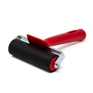 May include: A red handled roller with a black rubber roller. The roller is used for applying ink or paint.