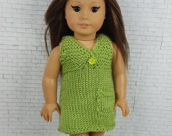 Könnte beinhalten: Ein grünes Strickkleid mit einer Tasche und einem Knopf vorne. Das Kleid wird von einer Puppe mit braunen Haaren getragen.