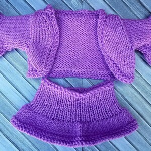 May include: A purple knitted cardigan and skirt set. The cardigan has a scoop neck and short sleeves. The skirt is A-line and hits above the knee.
