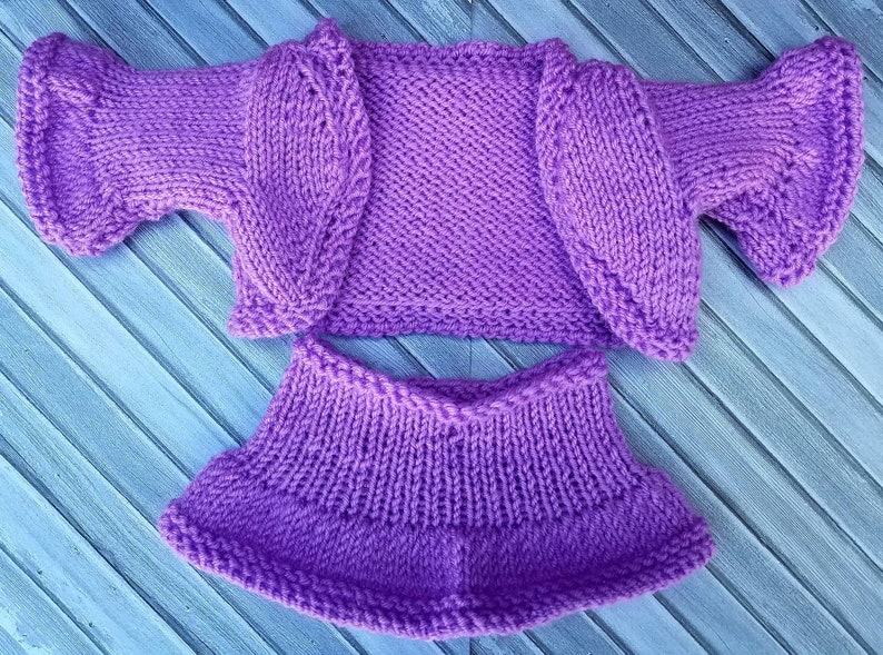 May include: A purple knitted cardigan and skirt set. The cardigan has a scoop neck and short sleeves. The skirt is A-line and hits above the knee.