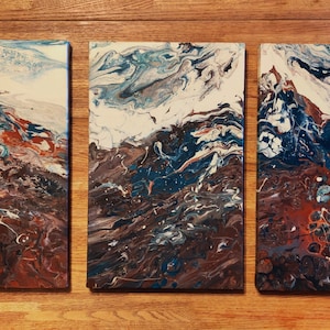 May include: A set of three abstract paintings with a swirling, marbled design in shades of brown, blue, white, and gray. The paintings are on canvas and are ready to hang.