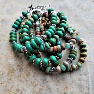 May include: A stack of turquoise and brown beaded bracelets with silver accents. The bracelets are made with different types of beads, including round, oval, and irregular shapes.