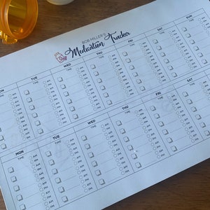 May include: A white medication tracker with a black and white pill bottle icon. The tracker has a grid layout with days of the week labeled at the top and time slots labeled down the side. Each day has a column for taking medication with checkboxes for AM and PM.