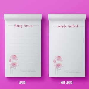 May include: Two white notepads with a magenta background. One notepad is lined and the other is not. Both have a floral illustration and the text "BREATHE IN DEEPLY AND LET YOUR LIFE UNFOLD". The lined notepad has the name "stacey herron" and the other has "pamela ballard".