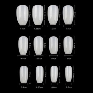 May include: Set of 12 white oval-shaped false nails with different sizes. The nails are measured in centimeters.