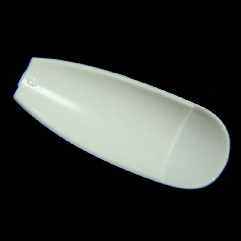 May include: A white plastic nail tip, shaped like a fingernail, for use in nail art and manicures.