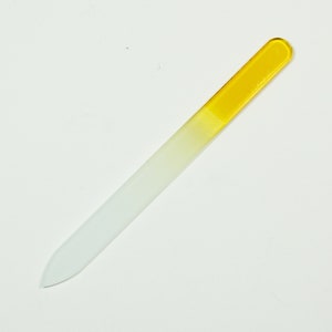 May include: A white glass nail file with a yellow tip. The file is designed for shaping and smoothing nails.