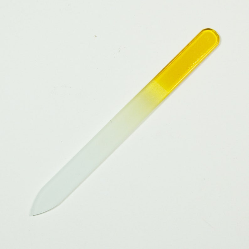 May include: A white glass nail file with a yellow tip. The file is designed for shaping and smoothing nails.