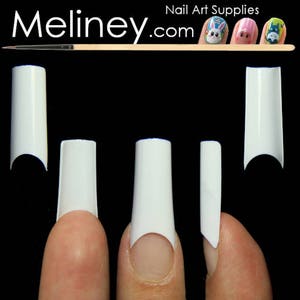 May include: Five white plastic nail tips of different sizes and shapes. The tips are shown on fingers, with the tips extending beyond the fingernail.