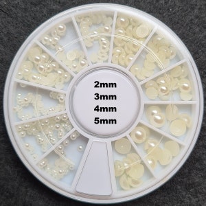 Pode incluir: Uma roda de pl&aacute;stico branca com 12 compartimentos contendo diferentes tamanhos de contas brancas peroladas. A roda &eacute; etiquetada com os tamanhos das contas: 2 mm, 3 mm, 4 mm e 5 mm.
