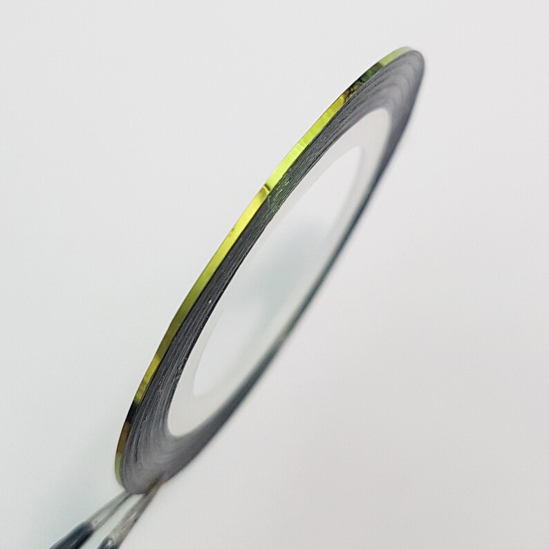 May include: A roll of gold nail art striping tape with a black backing.