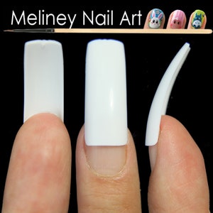 May include: Three white artificial nails, each with a different shape, are shown on fingers. The nails are square, oval, and stiletto.