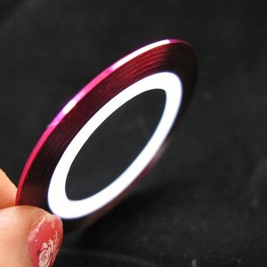 May include: A roll of pink metallic nail tape with a white stripe down the center.