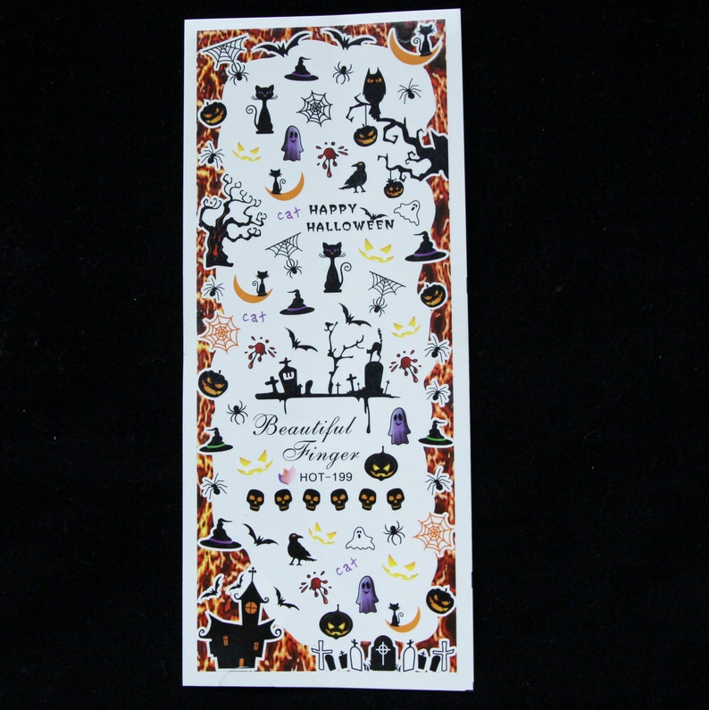 Puede incluir: Pegatinas de arte de u&ntilde;as de Halloween con im&aacute;genes de gatos, calabazas, fantasmas, murci&eacute;lagos, ara&ntilde;as, sombreros de bruja y un cementerio. Las pegatinas est&aacute;n sobre un fondo blanco con un dise&ntilde;o de llamas naranja y negro.