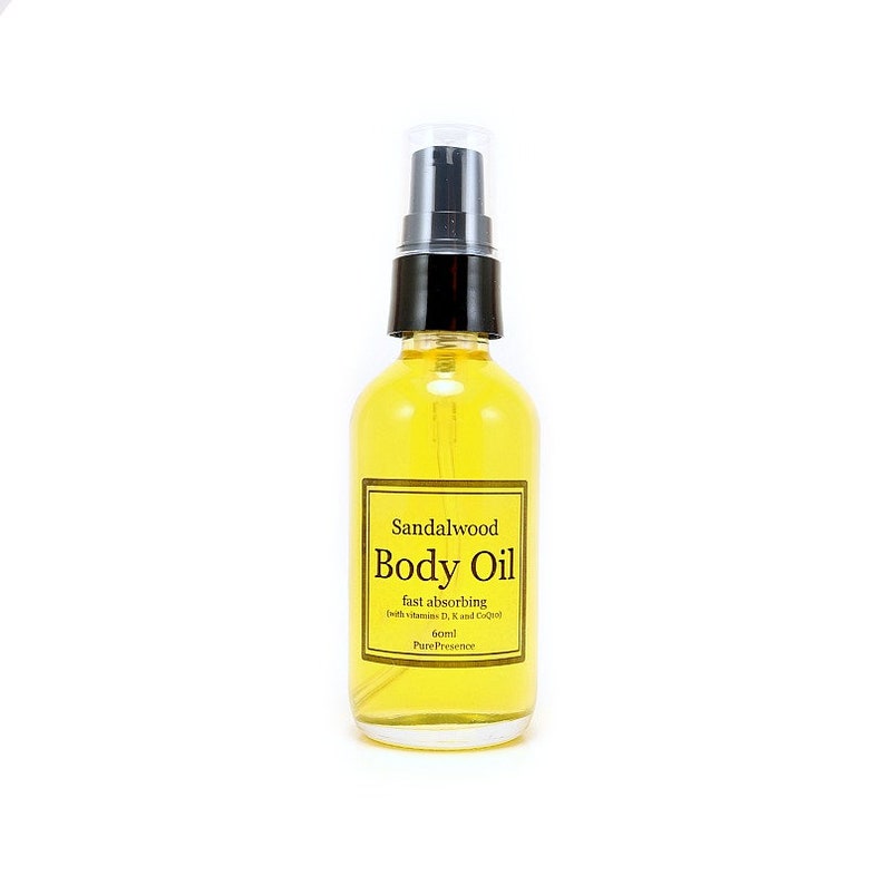 May include: A clear glass bottle with a black pump top filled with yellow body oil. The label reads "Sandalwood Body Oil fast absorbing (with Vitamins D, E, and Coconut Oil) 60ml Pure Presence".